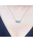 18K white gold necklace with a rectangular emerald-cut Colombian emerald and halo diamonds.