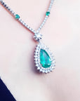 Pear cut emerald necklace with double diamond halo, 18K white gold chain with emerald accents.