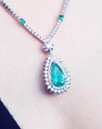 Pear cut emerald necklace with double diamond halo, 18K white gold chain with emerald accents.
