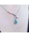 Pear cut deep green emerald necklace with diamond halo and accents, crafted in 18K white gold.