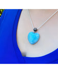 Heart-shaped blue and white Larimar pendant on a sterling silver chain, worn on a person's chest.