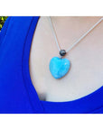 Heart-shaped blue and white Larimar pendant on a sterling silver chain, worn on a person's chest.