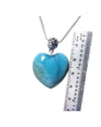 Larimar heart-shaped pendant on a silver chain with a ruler for scale on a white background