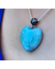 Heart-shaped blue and white larimar pendant on a sterling silver necklace, worn against skin.