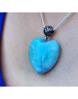 Heart-shaped blue and white larimar pendant on a sterling silver necklace, worn against skin.