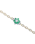 Gold bracelet with a clover-shaped emerald and diamond charm on a white background
