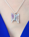 Lavender agate butterfly pendant necklace with sterling silver chain on a blue top.