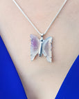 Lavender agate butterfly pendant necklace with sterling silver chain on a blue top.