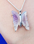 Butterfly-shaped natural agate pendant on a silver chain worn around the neck