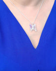 Lavender agate butterfly pendant necklace with sterling silver chain on a blue top.