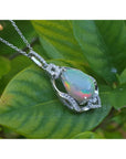 Pear-shaped rainbow Welo Ethiopian opal pendant in sterling silver with cubic zirconia accents on a leaf.