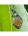 Oval Ethiopian opal pendant with vibrant play of colors and brown pinpoint fire, wire-wrapped in silver.