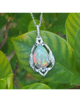 Opal pendant necklace on a silver chain with a green leaf background.
