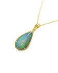 left side profile of an opal pendant necklace on a gold chain against a white background