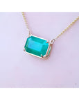 Emerald-cut Colombian emerald solitaire necklace in 18K yellow gold.