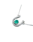 14K white gold horseshoe necklace with oval emerald and natural diamonds.