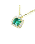 1.31 ct emerald-cut Muzo Colombian emerald necklace with diamond halo in 14K yellow gold.