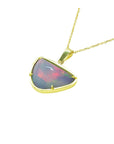 Opal pendant on a gold chain on a left-side profile against a white background.