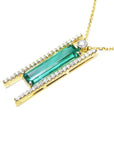 Left side of a gold necklace with a natural baguette cut emerald gemstone and side round diamonds on a white background
