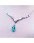 A left side view of a white gold 14k necklace with tear drop emerald in a halo natural diamond