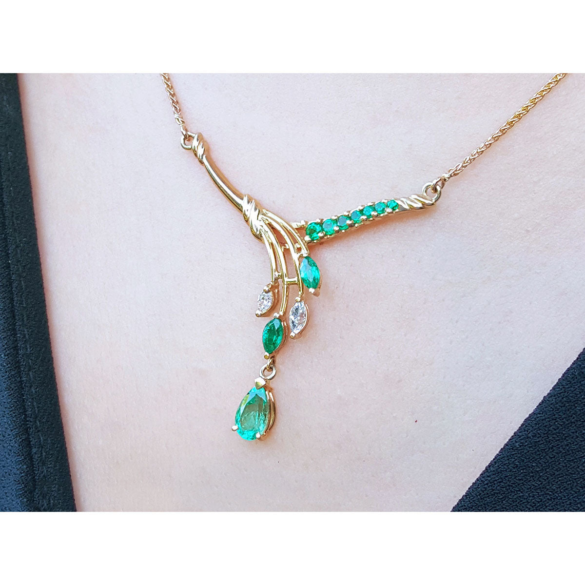 A left side view of a 14k yellow-gold necklace with Muzo emeralds and diamonds gemstones on a person's neck