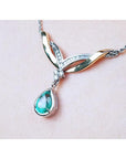 A left side jewelry necklace with a dangling teardrop emerald gemstone solitaire pendant on woman's collar
