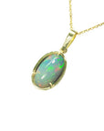 Ethiopian Welo opal pendant with gold frame on a left-side profile on a white background.
