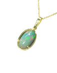 Ethiopian Welo opal pendant with gold frame on a left-side profile on a white background.