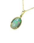 Oval Ethiopian opal pendant with bluish-green hues, prong-set in 14K yellow gold on a delicate chain.