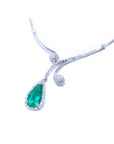 Left side of a white gold necklace with an emerald teardrop halo diamond pendant on a white background