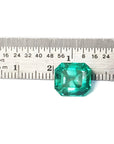 4.71 carat emerald-cut Colombian emerald, medium bluish-green, next to a ruler for scale.