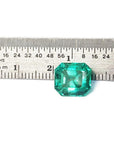4.71 carat emerald-cut Colombian emerald, medium bluish-green, next to a ruler for scale.