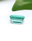 1.83 carat emerald-cut Colombian emerald with a vibrant bluish-green hue on a white background.