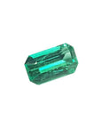 Emerald gemstone, rectangular cut, deep green, isolated on white.