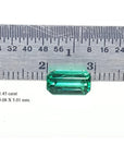 1.45 carat emerald gemstone, 9.08 X 5.01 mm, shown with a ruler for scale.