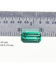 1.45 carat emerald gemstone, 9.08 X 5.01 mm, shown with a ruler for scale.