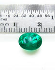 2.11 ct oval cut deep bluish-green Colombian emerald next to a ruler for scale.
