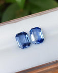 2.16 ct. Loose matching pair blue sapphires emerald-cut, frontside position tables and crowns visibles on a display