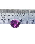 Loose round cut natural pink sapphire upside position table and crown visibles next to a ruler sizer