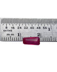 Deep red 1.07 ct. natural loose Burma ruby, tapered baguette cut, next to a ruler.