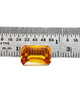 4.05 ct. vibrant intense yellow emerald-cut natural sapphire gemstone next to a ruler.