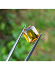 2.96 ct. loose natural yellow Madeira radiant cut sapphire held by tweezers.