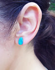 Pear-shaped deep blue Australian doublet opal earring on an ear.