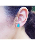 Pear-shaped deep blue Australian doublet opal earring on an ear.