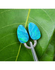 Pear-shaped, deep blue Australian doublet opals, 4.45 ct, held by tweezers on a green leaf.