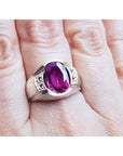 Oval-cut natural pink sapphire ring with sparkling medium pink stone and white accents on a hand.