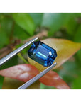 3.53 ct GIA certified natural greenish-blue sapphire, rectangular emerald cut, held by tweezers.