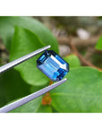 3.53 ct GIA certified natural greenish-blue sapphire, rectangular emerald cut, held by tweezers.