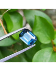 3.53 ct GIA-certified natural greenish-blue sapphire, rectangular emerald cut, held by tweezers.