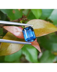 GIA-certified 3.53 ct. natural greenish-blue sapphire, rectangular emerald cut, held by tweezers.